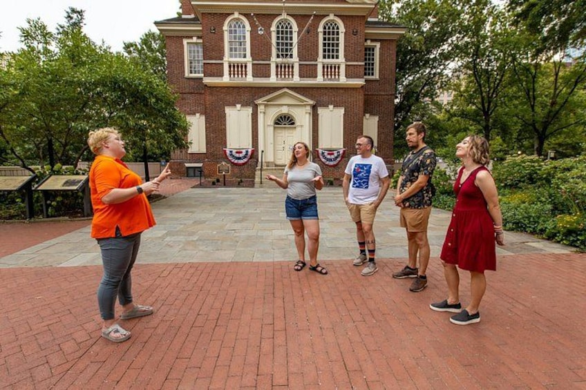 A group of people standing in front of a brick building with a flag. 4