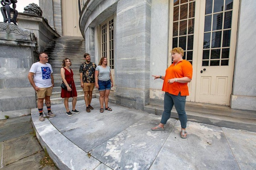 A group of people standing on a stone-paved area in front of a building with large windows and a door. 2