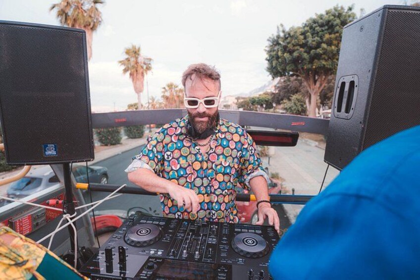 A person operating DJ equipment in a vehicle with large speakers. 2