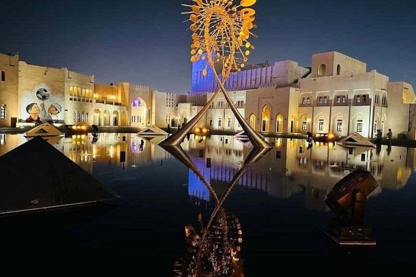 A nighttime view of a waterfront with illuminated buildings and a large, ornate structure reflecting on the water. 3