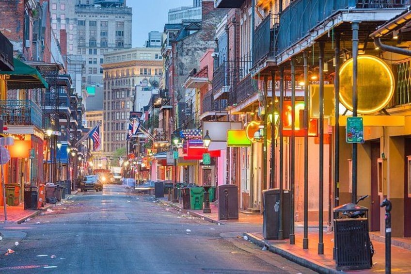 A street lined with buildings, some with illuminated signs, and a few flags. 2