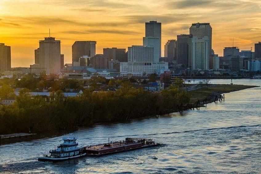 A river with a boat, a city skyline, and a sunset. 3