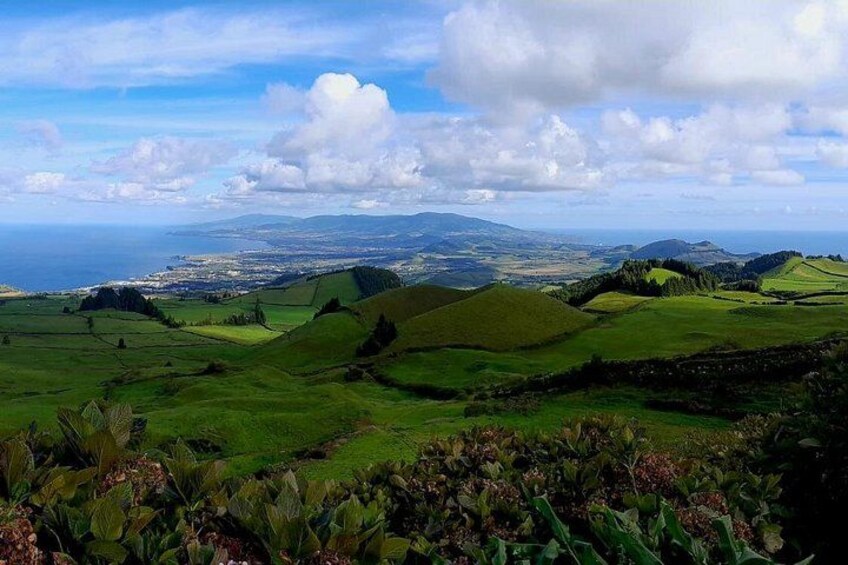 Rolling green hills, a distant coastline, and a clear sky. 4
