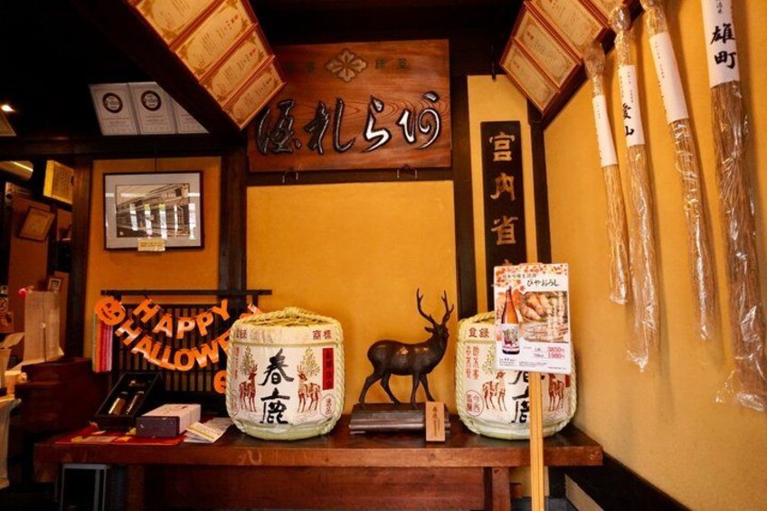 Een restaurantinterieur met een 'Happy Halloween'-bord, een hertenbeeldje en traditionele Japanse decoraties. 2