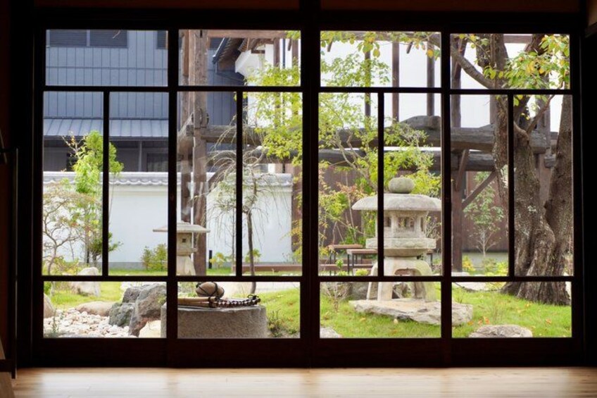 Een traditionele Japanse tuin met stenen lantaarns, een vijver en een houten constructie. 5
