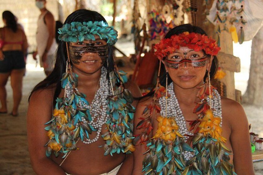 Two individuals wearing elaborate traditional costumes with feathered headdresses and jewelry. 5