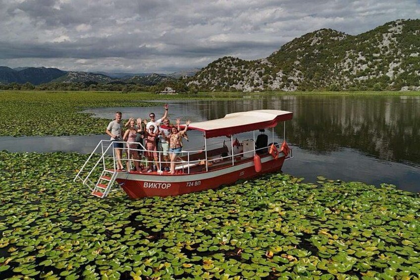 A boat named 'ВИКТОР' on a lake surrounded by greenery and hills. 3