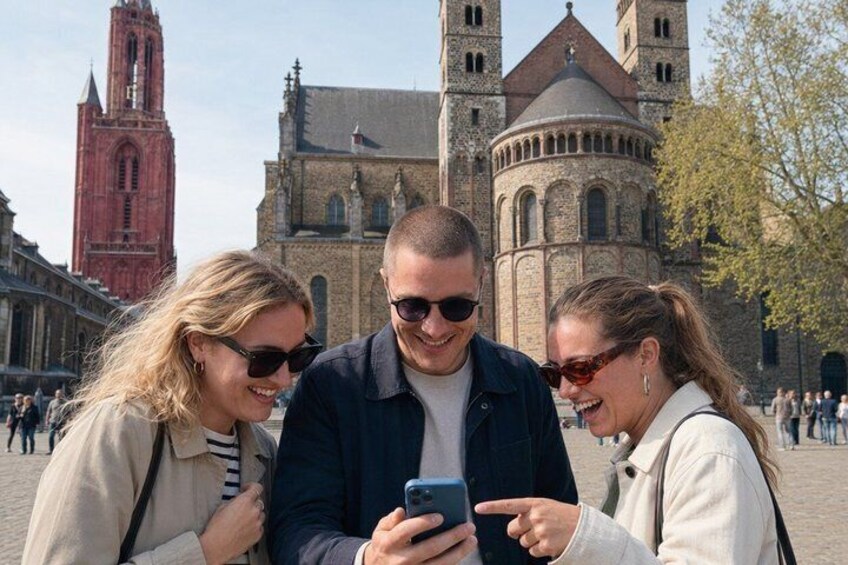 Three people looking at a smartphone, with historic buildings in the background. 3