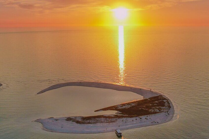 Un banc de sable en forme de croissant, illuminé par le soleil couchant dont les rayons se reflètent sur l’eau. 3