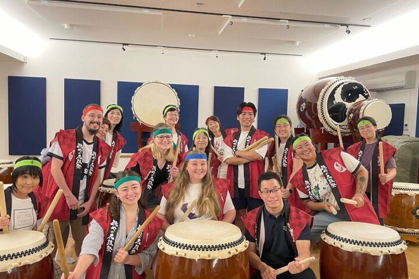 A group of people in a room with musical instruments, including drums and a large drum set. 5