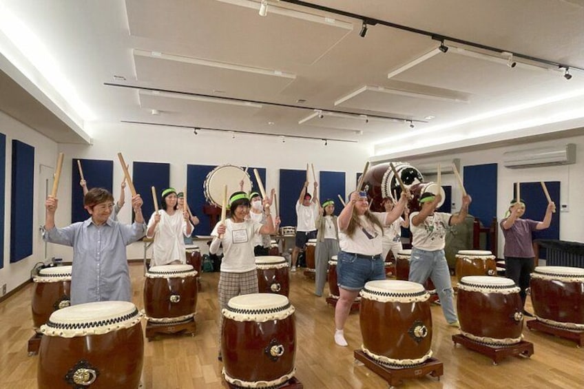 A group of people in a room with musical instruments, including drums and a large drum. 4