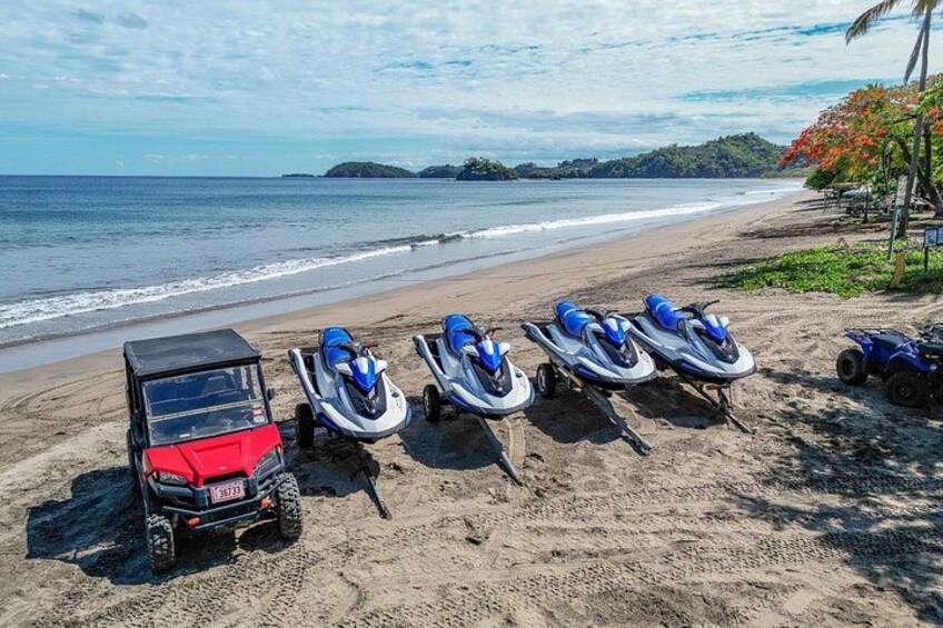 A beach with jet skis and a red off-road vehicle. 2