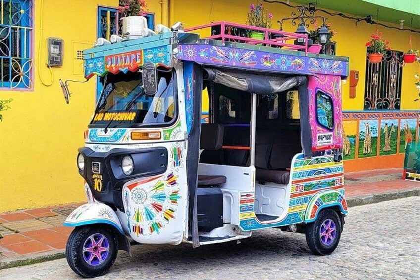 A colorful auto rickshaw parked on a cobblestone street. 5