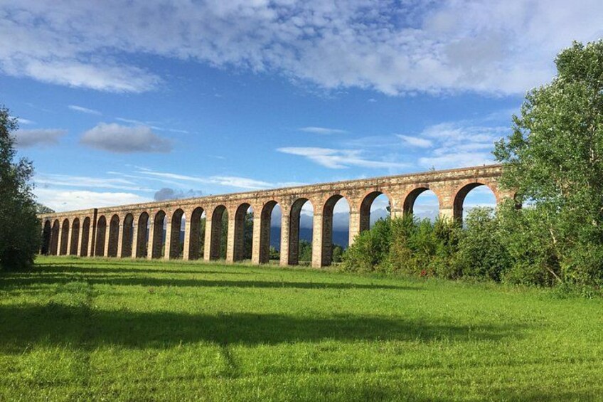 A long viaduct with multiple arches, surrounded by green grass and trees. 2