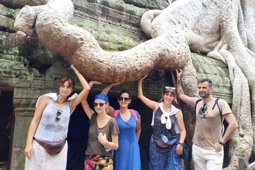A group of people posing in front of a large stone sculpture. 1