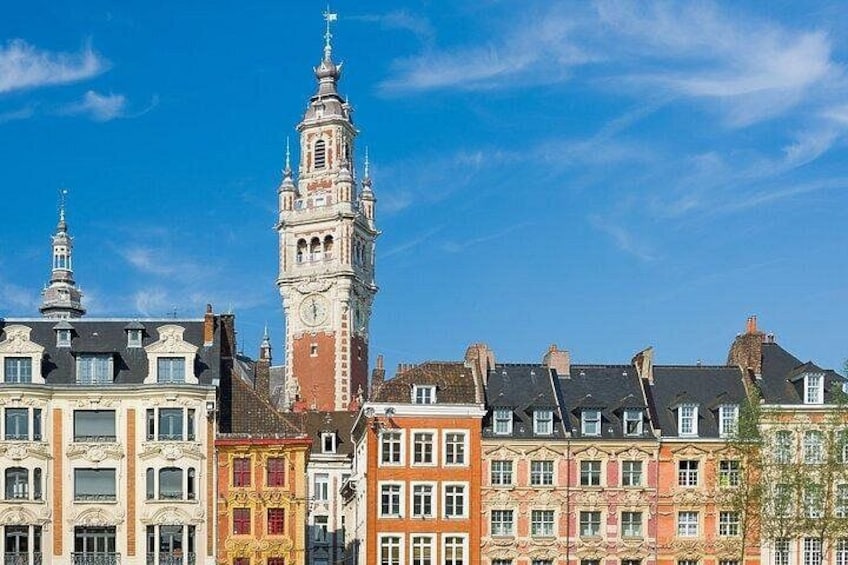 Una città storica con una torre dell'orologio imponente, edifici tradizionali e un cielo azzurro intenso. 1