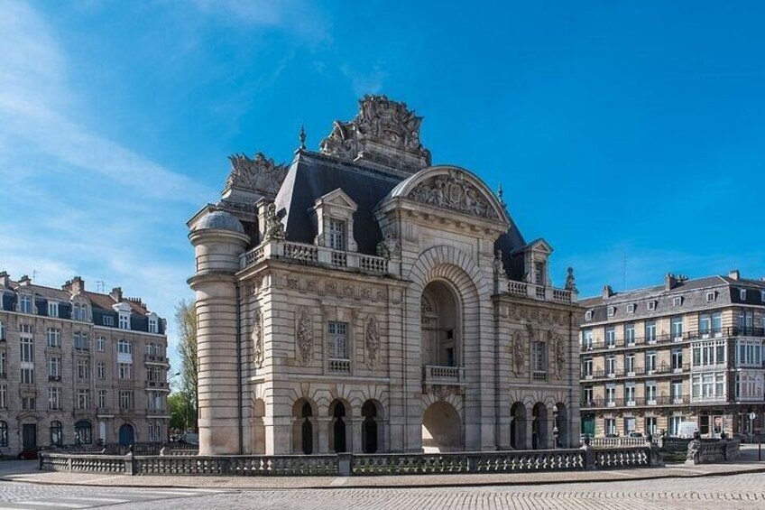 A historic building with ornate architecture, a prominent arched entrance, and a surrounding cobblestone plaza. 4