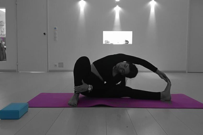 A person performing a yoga stretch on a purple mat in a room with white walls and a door. 1