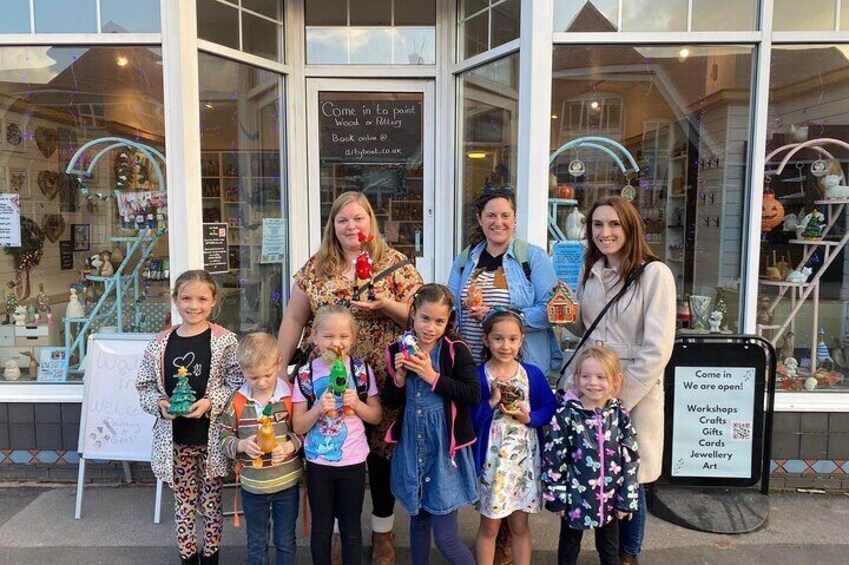 A group of people standing in front of a shop with a sign that reads "Come in to paint Wood or Felting Book online @ artybook.co.uk". 5