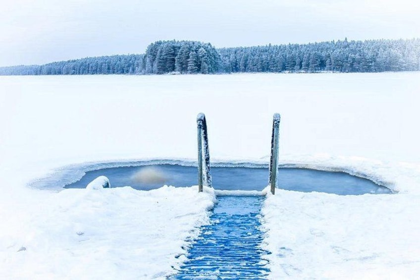A frozen lake with a hole in the ice, surrounded by snow-covered trees. 4