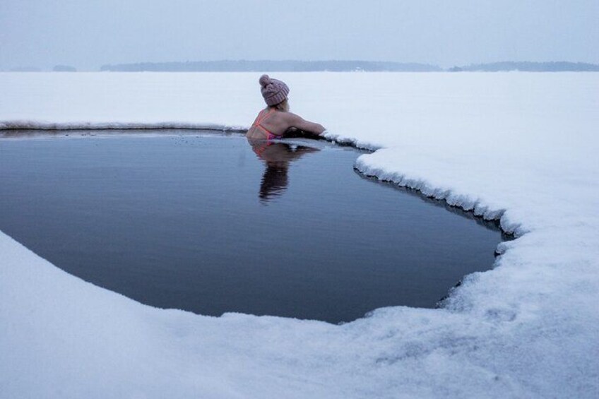 Una persona sentada en una piscina de hielo circular rodeada de nieve. 3