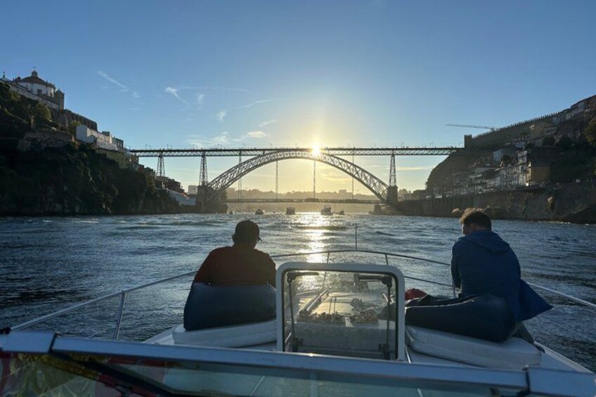 Un bote con dos personas en un río, un puente al fondo y edificios a orillas del río. 5