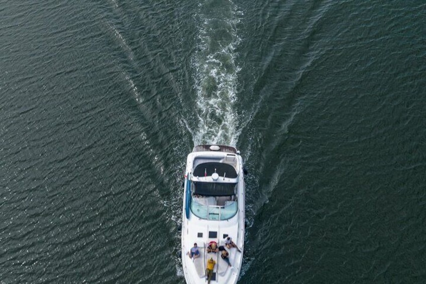 Un bateau à la coque blanche et au toit bleu, qui se déplace sur une étendue d’eau, laissant une vague derrière lui. 5