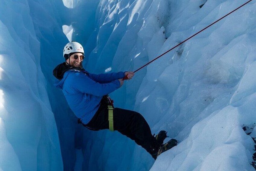 A person ice climbing in a narrow, icy crevasse. 4