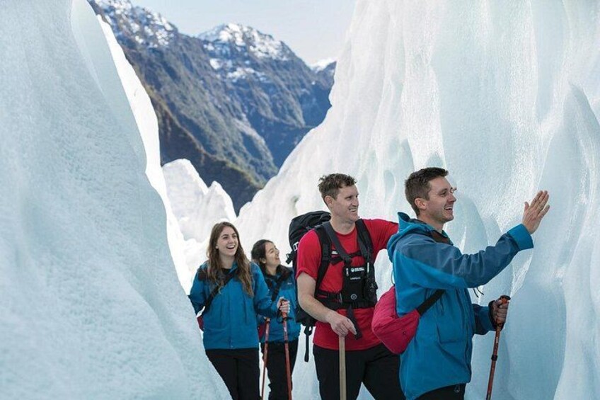 A group of hikers in a glacier with ice walls and mountains in the background. 3