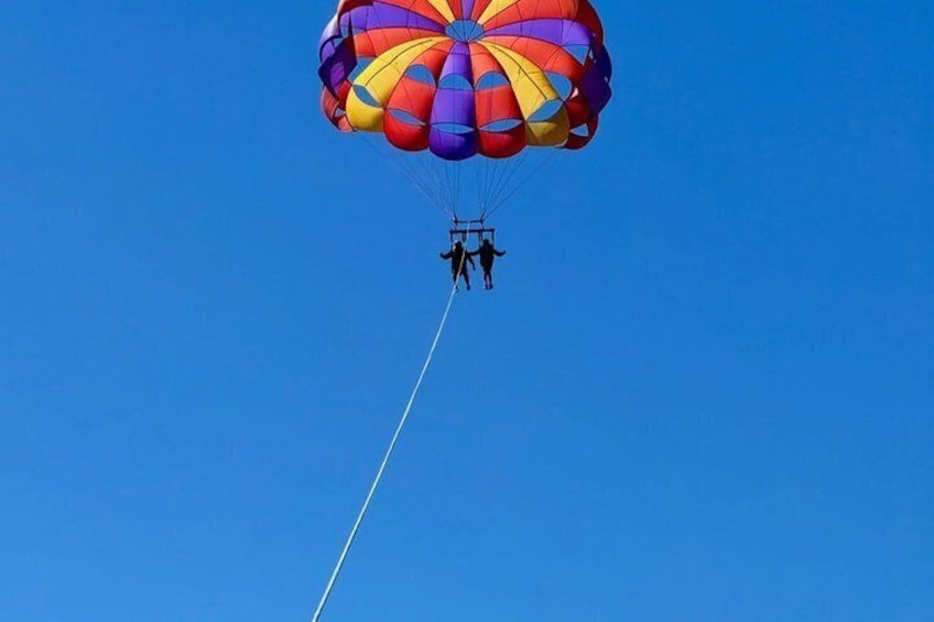 Une personne pratiquant le parachutisme avec un parachute aux couleurs vives, sur fond de ciel bleu dégagé. 3