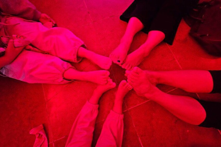 A group of people sitting in a circle on a red floor. 2