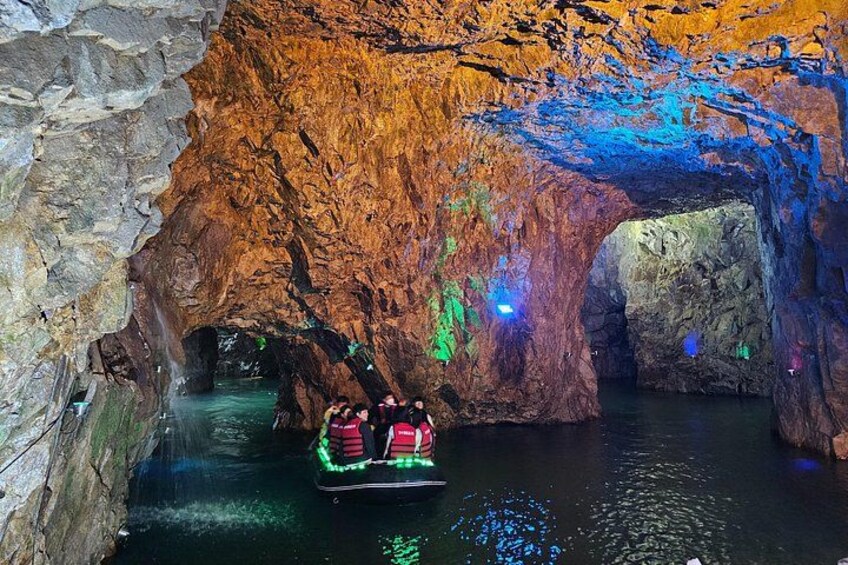 A boat ride through a cave with illuminated walls and water. 1