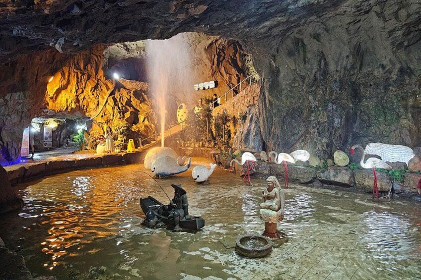 A cave with a water feature, a large white elephant sculpture, and a person in a lotus position. 3