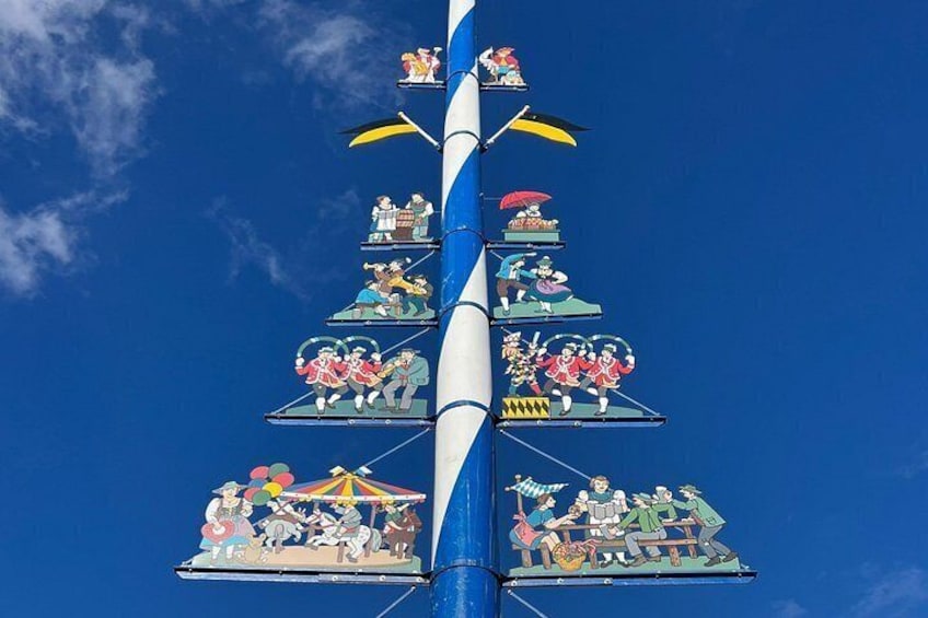 Una struttura verticale a più livelli, ciascuno decorato con figure e scene colorate, sullo sfondo di un cielo azzurro. 4