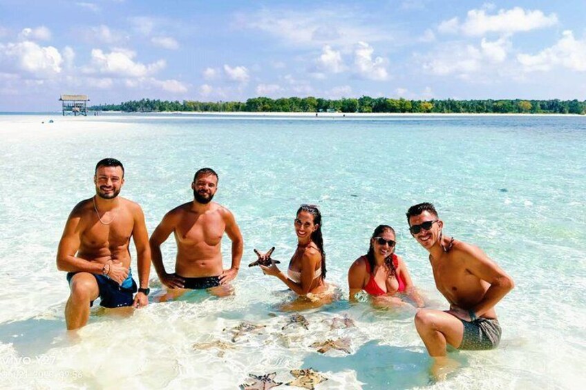 A group of people in shallow water with a clear sky and a distant shoreline. 3