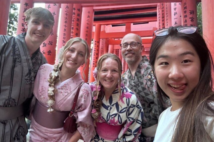 Un grupo de personas frente a un torii rojo con caracteres japoneses. 2