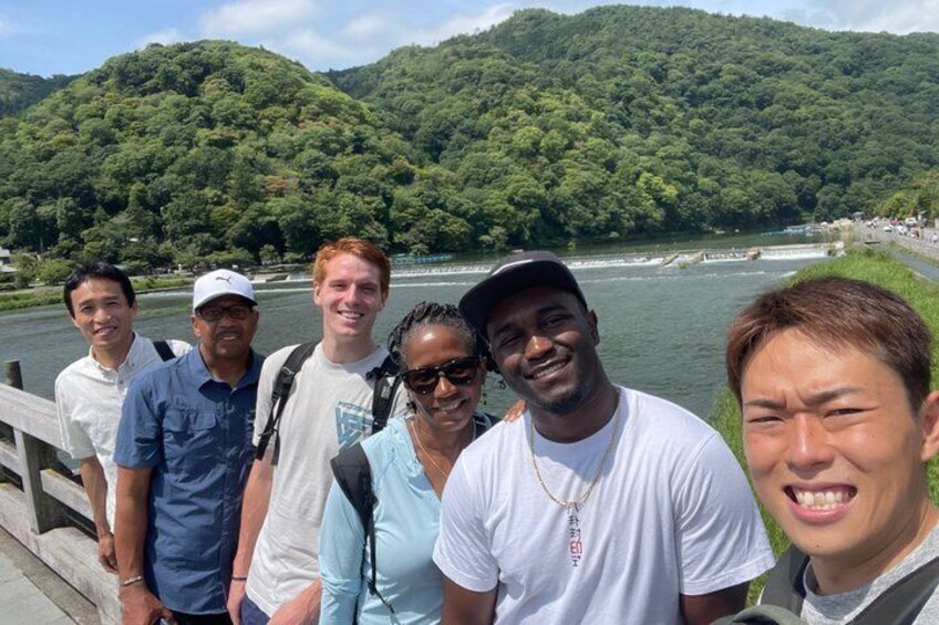 Un grupo de personas sobre un puente, con un río y colinas boscosas al fondo. 4