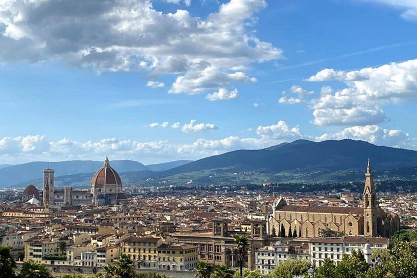Un paisaje urbano con edificios destacados de cúpulas y torres, una cordillera al fondo y un cielo despejado. 1