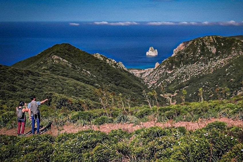 A mountainous landscape with a view of the ocean, a person pointing, and another person taking a photo. 2
