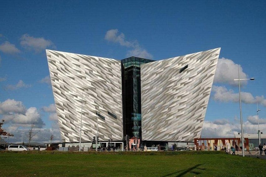A modern building with a unique geometric facade, surrounded by a grassy area and a clear sky. 5