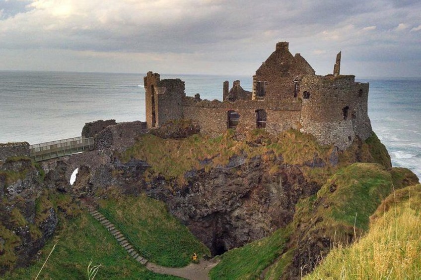 A coastal castle ruins with a pathway leading to it, overlooking the sea. 3