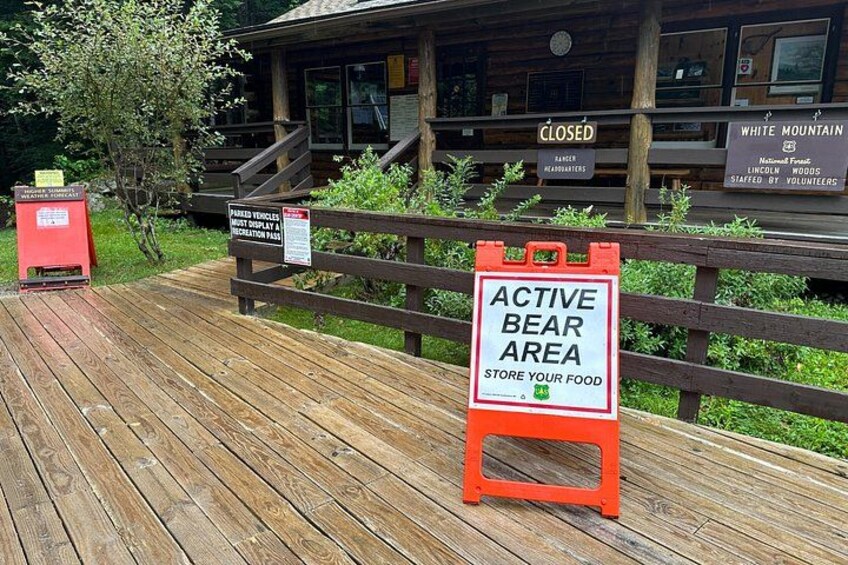 A wooden deck with a sign indicating an active bear area and a closed building in the background. 4