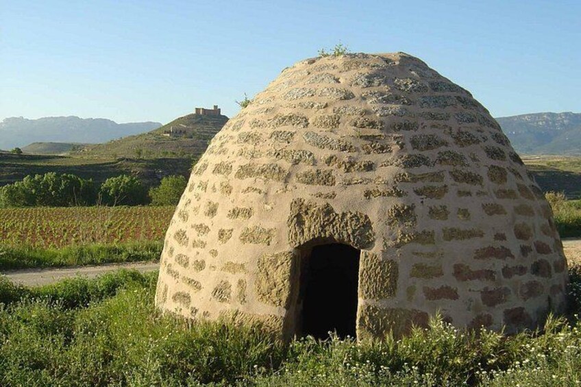 Una estructura tradicional de cúpula de piedra en un paisaje rural con colinas al fondo. 5
