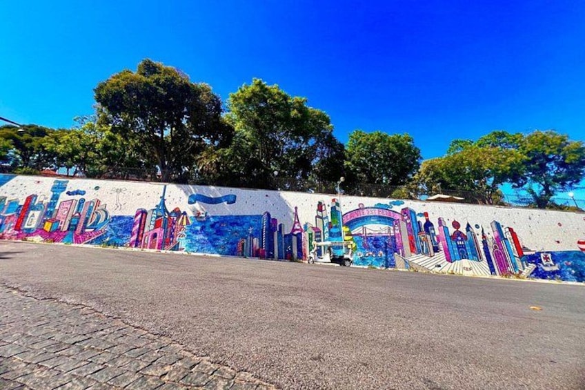 Un mural colorido en una pared, con árboles al fondo. 2