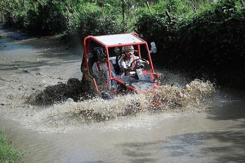 Un vehículo rojo atravesando un arroyo embarrado. 4
