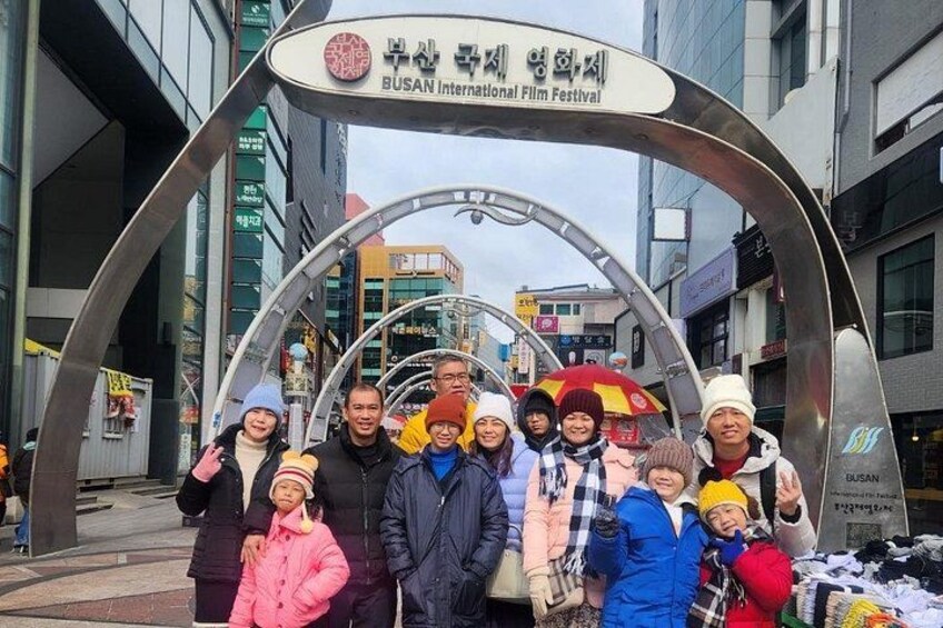A group of people posing in front of a sign for the Busan International Film Festival. 1