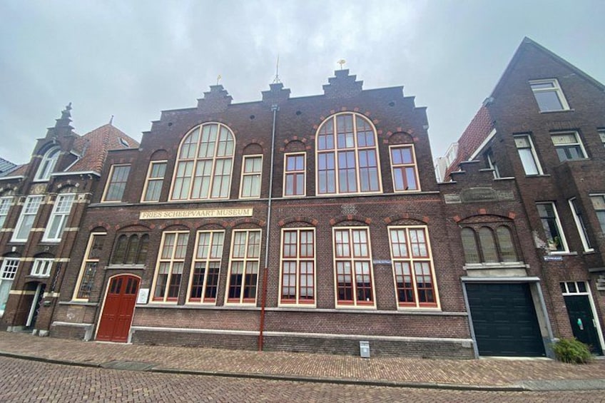 A historic building with large arched windows and a red door, labeled as a museum. 2