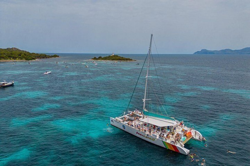 A sailboat with passengers, surrounded by clear turquoise waters and distant islands. 4