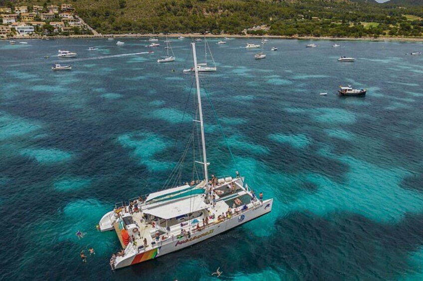 Un voilier transportant des passagers sur une mer turquoise, avec d’autres bateaux en arrière-plan. 1