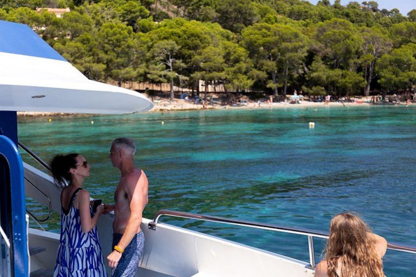 A boat on a clear blue sea with a beach and trees in the background. 3